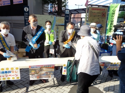 市長が啓発品の梨を駅利用者へ渡す様子