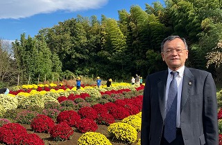 ざる菊園をバックに見学する落合市長