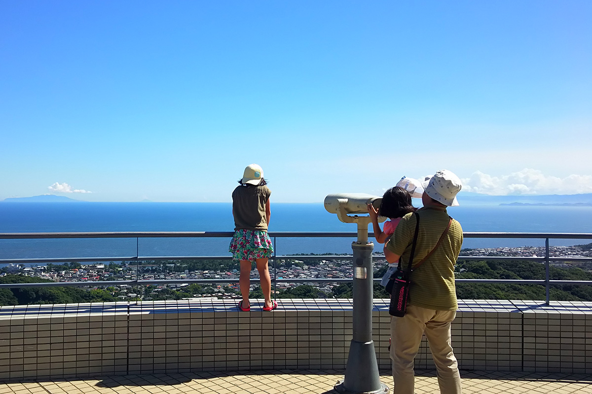 展望台から海を眺める親子の写真