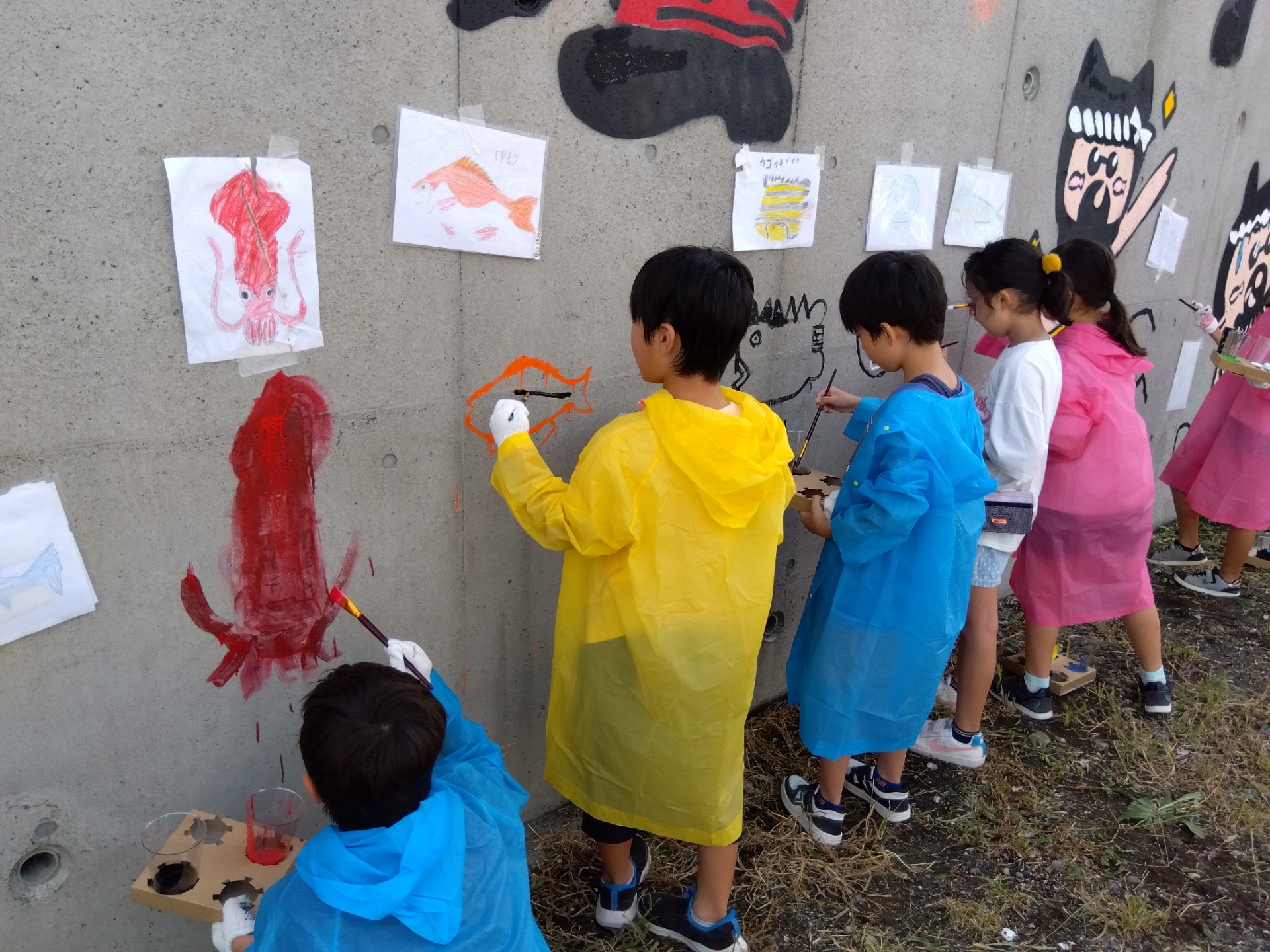 小学生が壁に海の生き物を描いている様子
