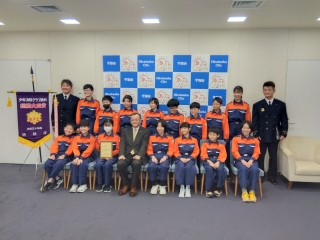 市長と平塚市少年消防クラブが応接室内で集合写真を撮る様子