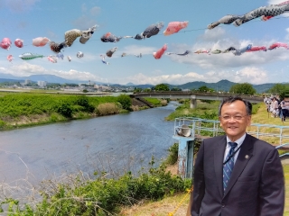 鈴川鯉のぼりまつり会場にて市長が鯉のぼりを背景に写真を撮る様子