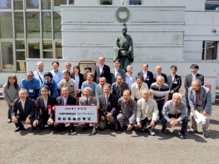 岡崎公民館での岡崎地区コミュニティタクシー実証実験出発式での集合写真を撮る様子